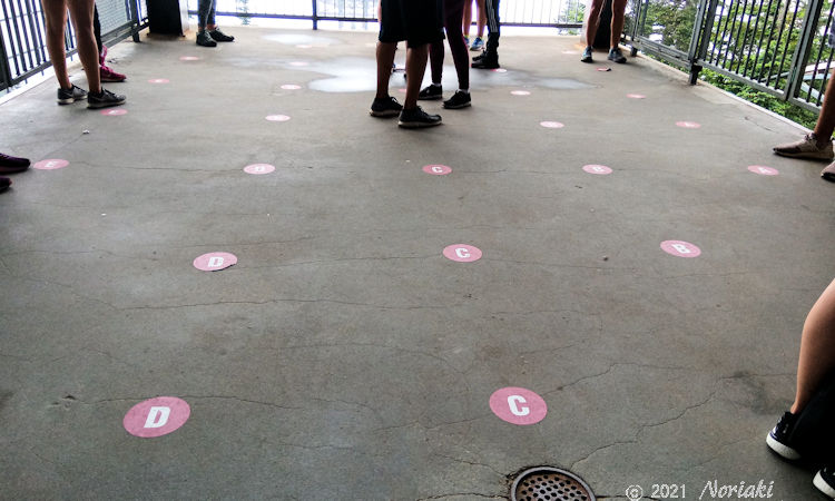 グラウス山のゴンドラ乗り場待機所の地面コンクリートにABCDE の5列ステッカーを張りつけた様子