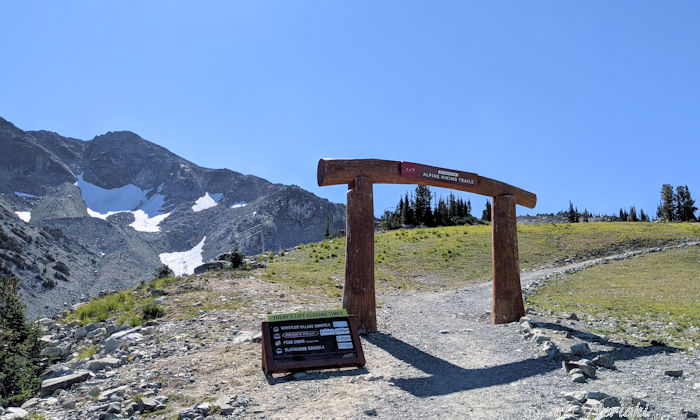 後ろにセブンスヘブン裏側の崖とアルパインハイキングトレイルの門